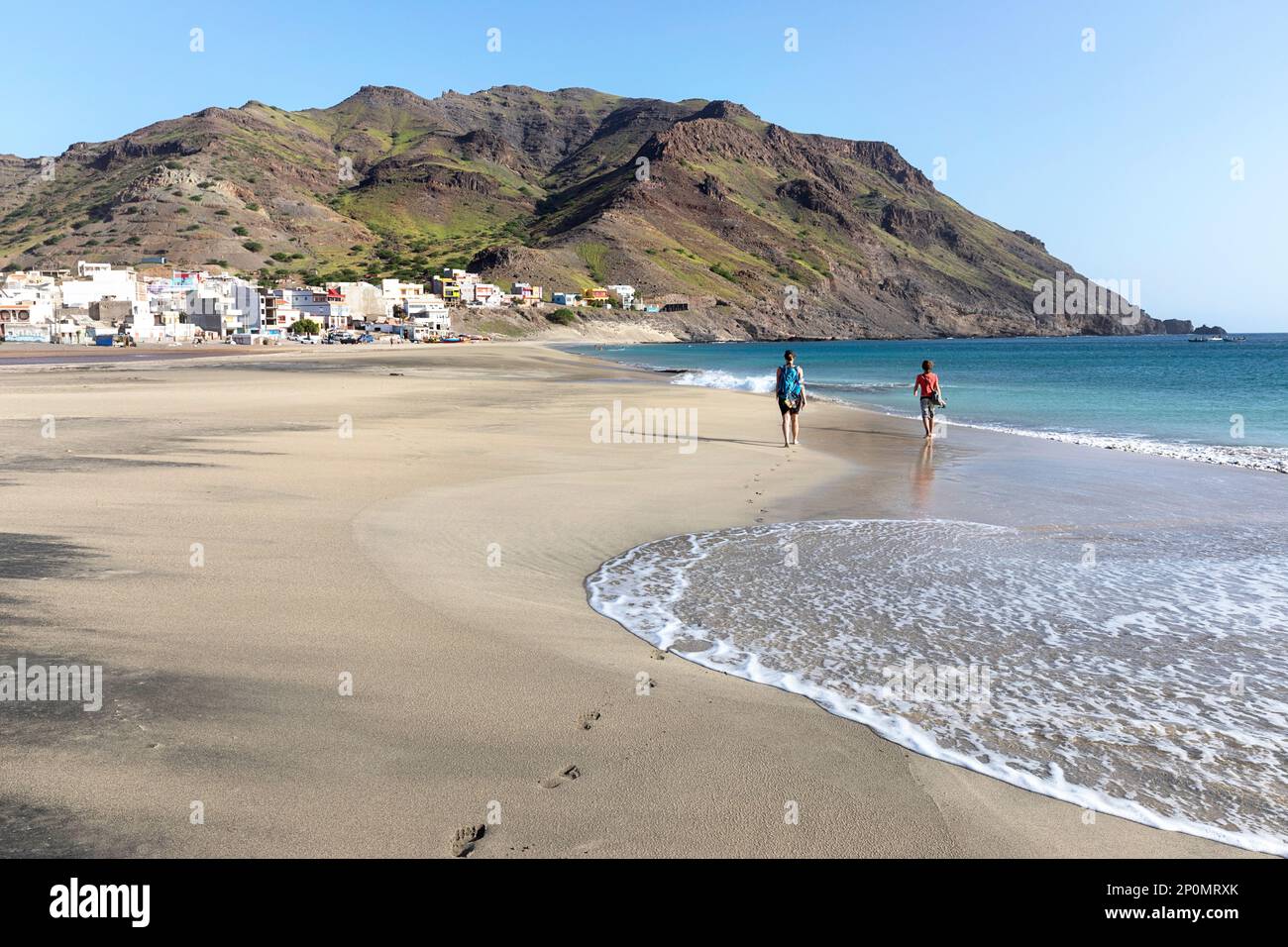 Mother and son on a family trip walking on a beautiful Sao pedro sandy beach with fishing village and mountains at the back, Sao vicente, Cabo verde Stock Photo