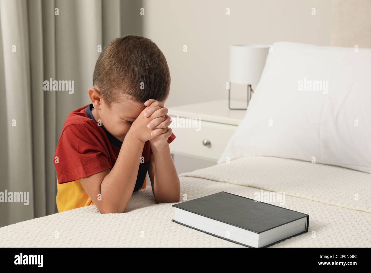 Cute little boy with hands clasped together saying bedtime prayer over ...