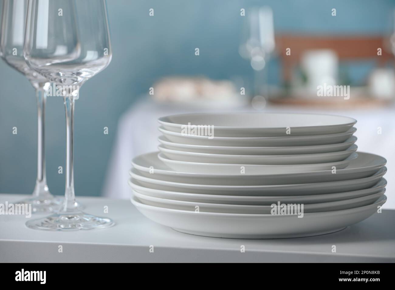 Stacked clean dishes and glasses on white shelf indoors Stock Photo Alamy