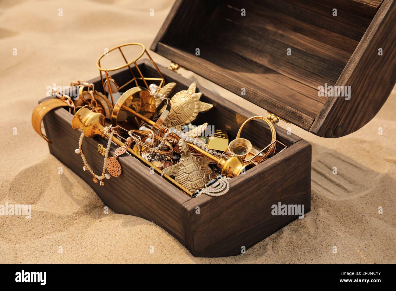 Open wooden chest with treasures on sand Stock Photo Alamy