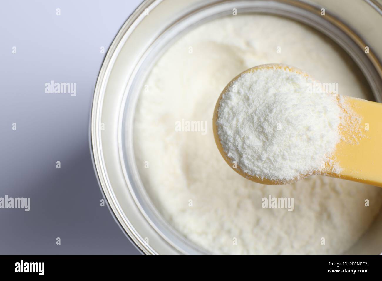 Scoop of powdered infant formula over can, top view. Baby milk Stock
