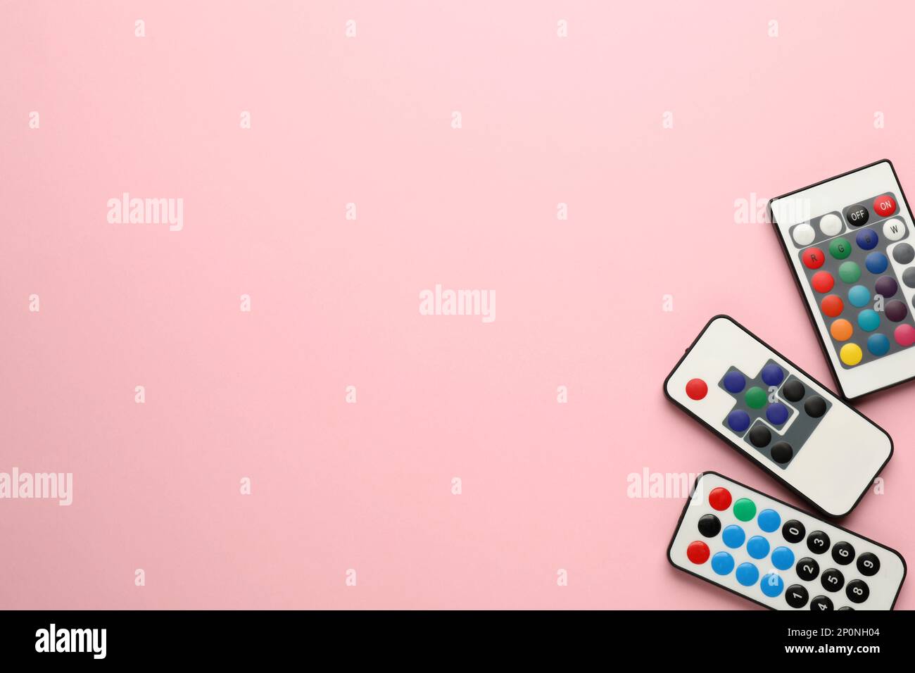 Different remote controls on pink background, flat lay. Space for text Stock Photo