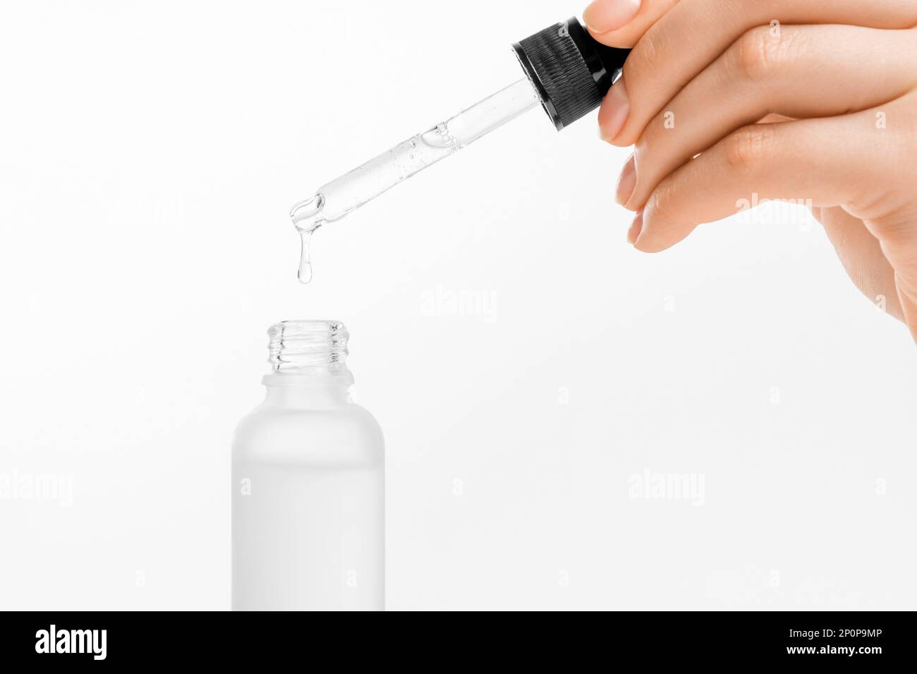 Woman hand holding pipette with collagen moisturizing hyaluron serum and drops the clear serum into the bottle. Stock Photo