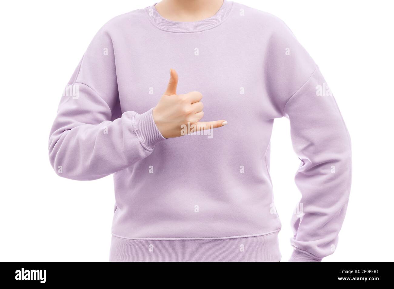 Cropped shot of a woman in a lavender oversized sweatshirt is showing hang loose shaka sign. Stock Photo