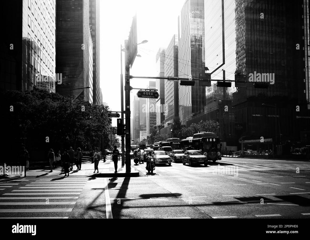 Seoul, South Korea - May 2019:  Seoul road crossing black and white photography with sun illumination and people, car silhouettes Stock Photo