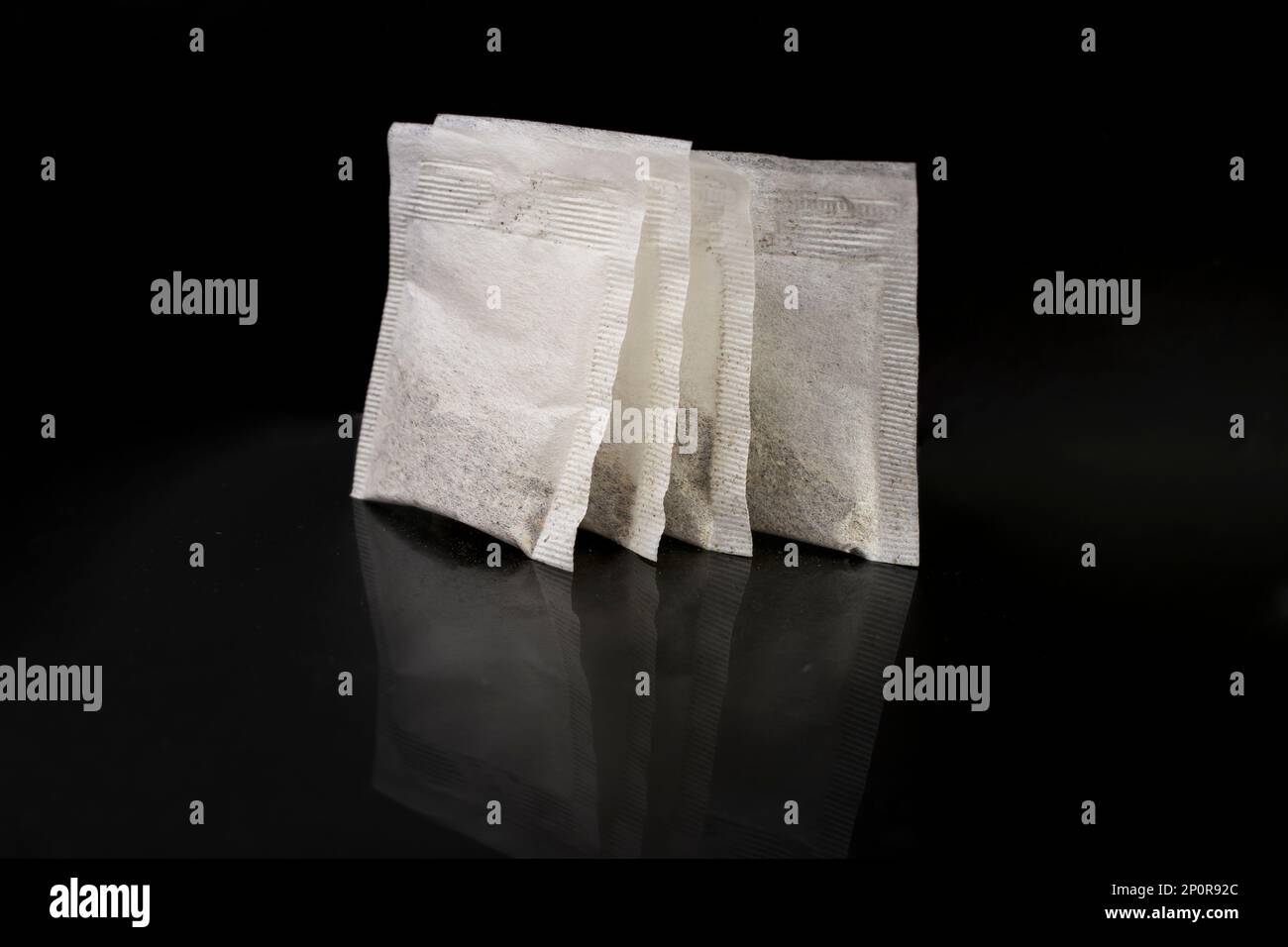 4 paper tea bags isolated on black background with reflection, close up