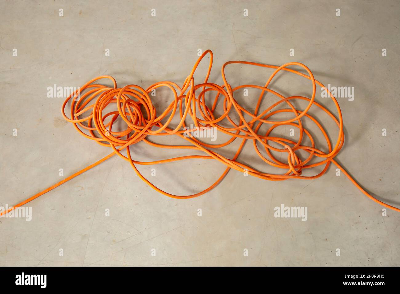 Tangled orange electrical cord, impossible problem concept Stock Photo