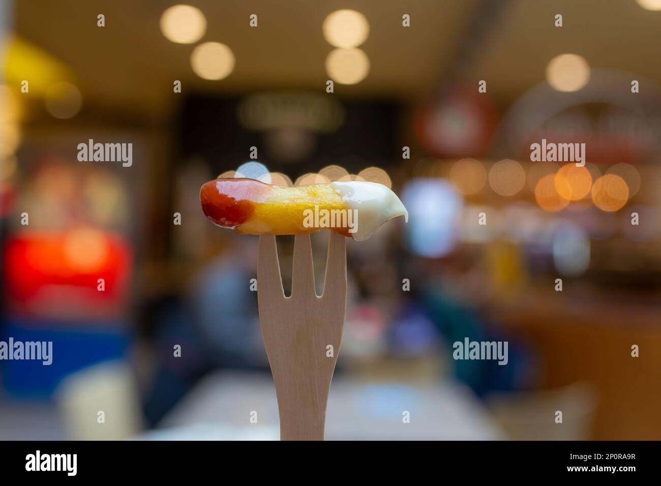 Wooden fork with a potato chip, dipped in mayonnaise and ketchup, with