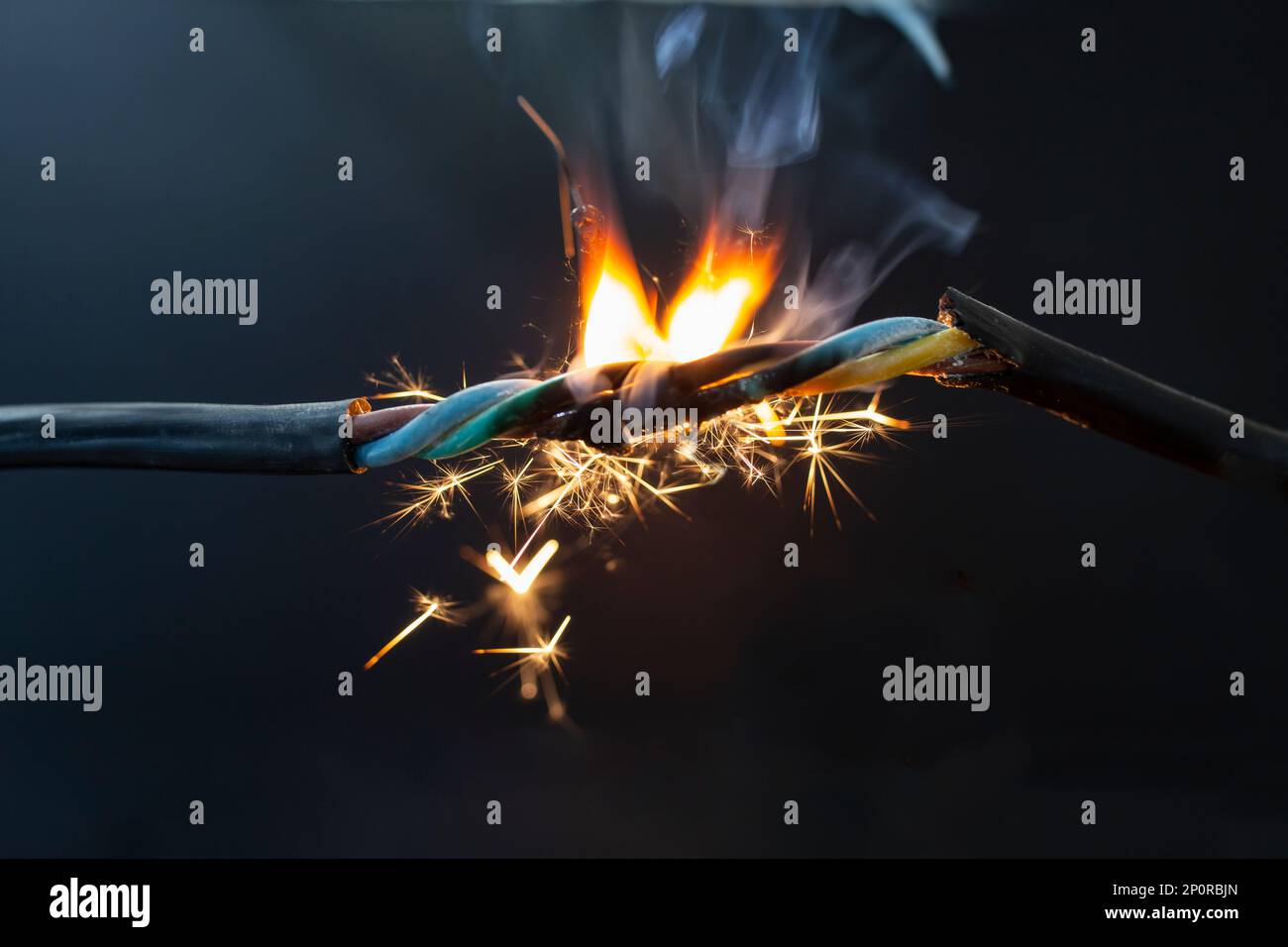 flame smoke and sparks on an electrical cable, fire hazard concept, soft focus close up Stock