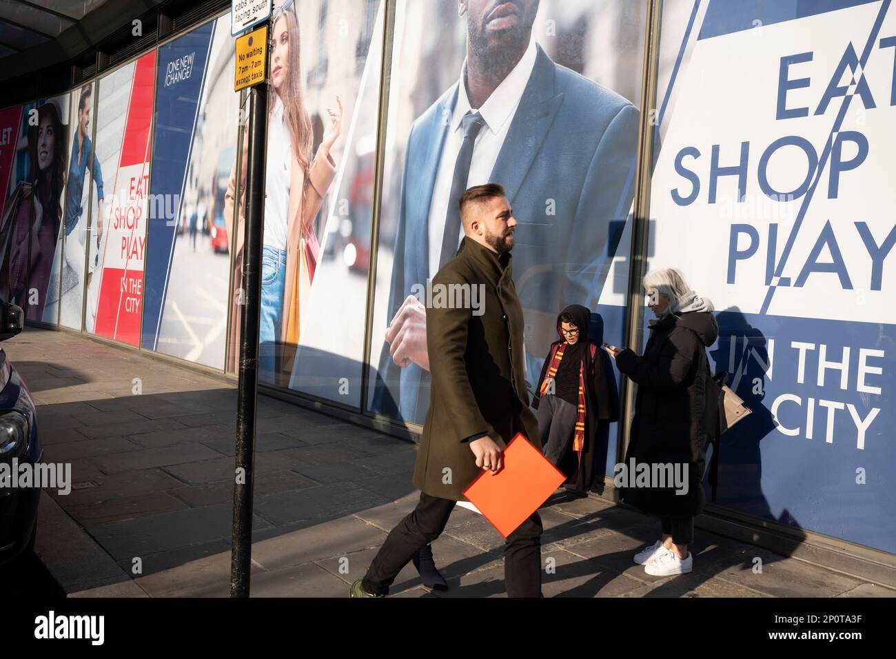 Passers-by and a new retail space opportunity hoarding in the City of London, the capital's financial district, on 2nd March 2023, in London, England. Stock Photo