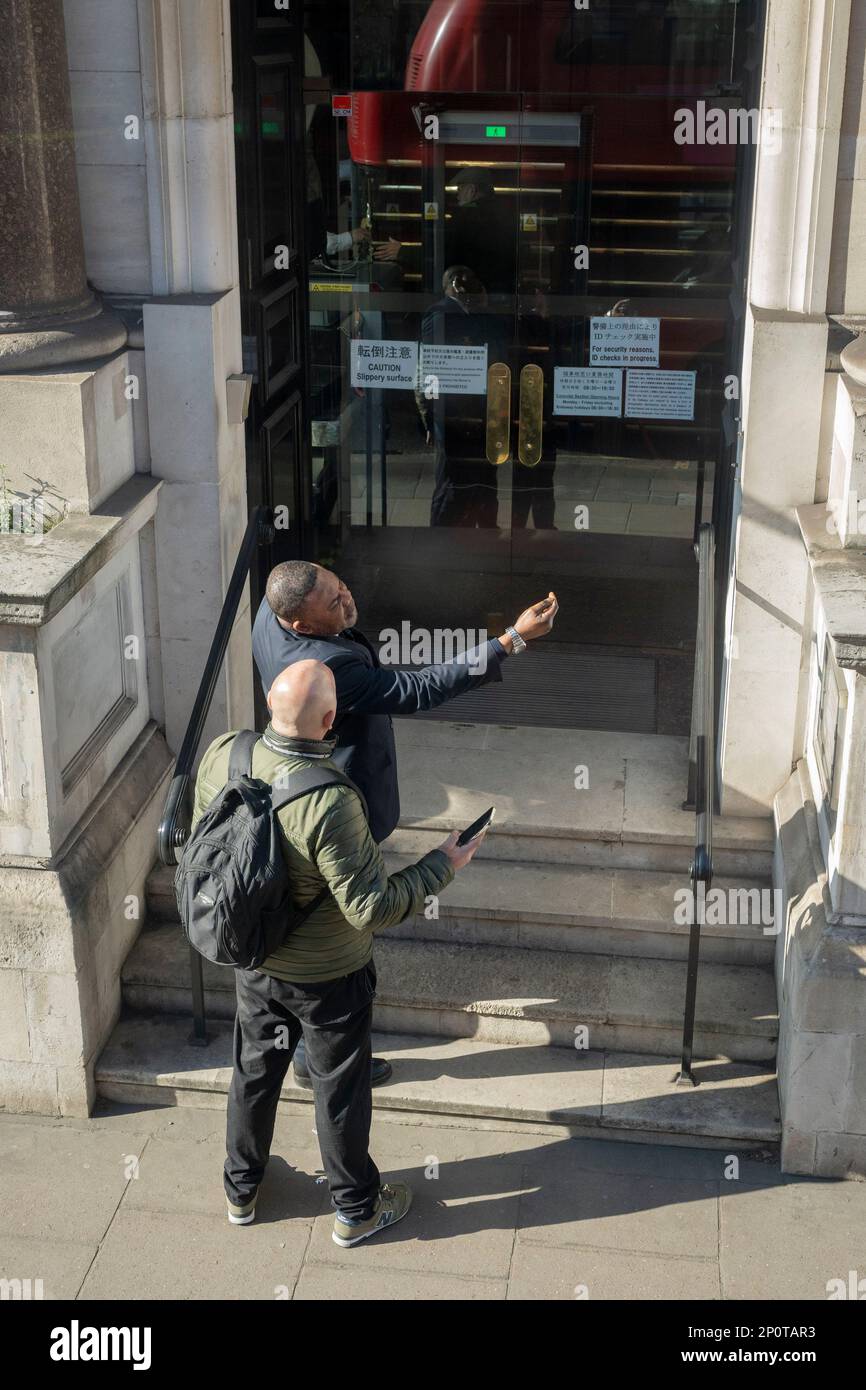 A doorman gives directions to a passer-by on the steps to the Japanese Embassy on Piccadilly, on 2nd March 2023, in London, England. Stock Photo