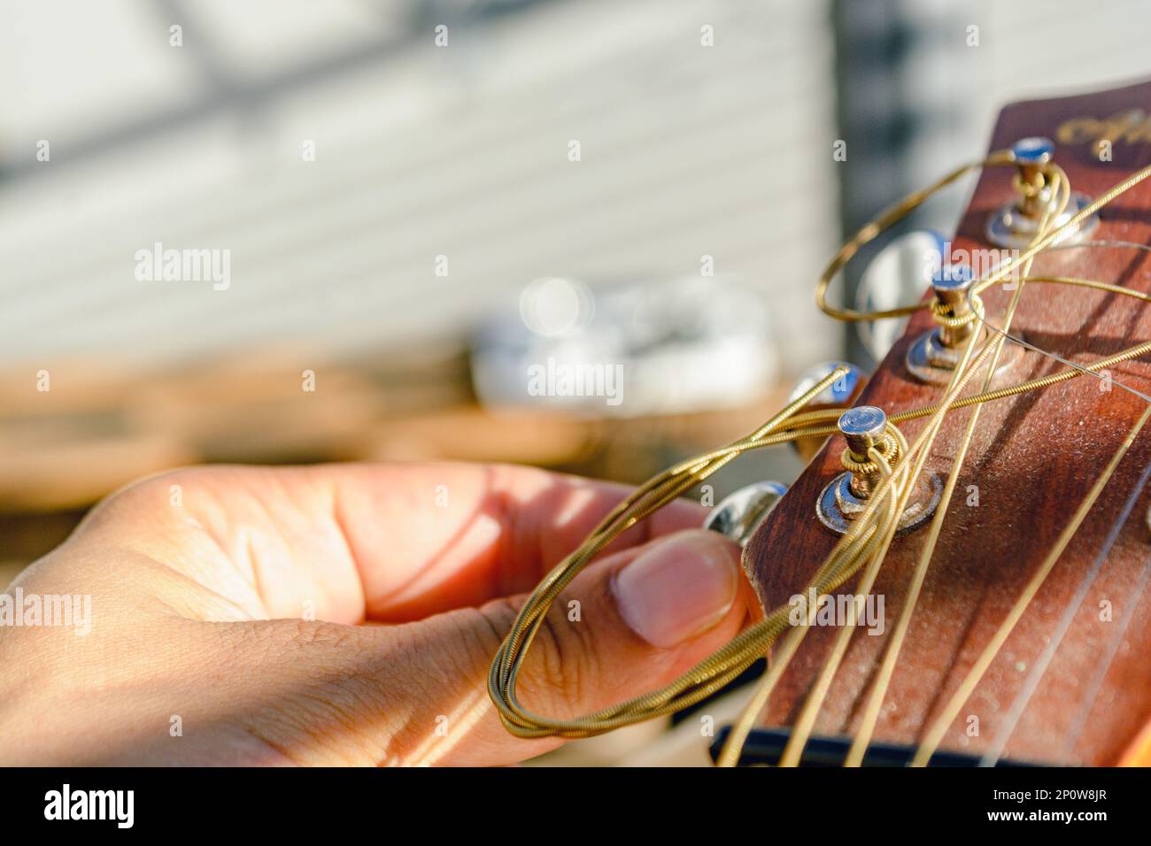 closeup of male hand tuning acoustic guitar, turning the guitar peg