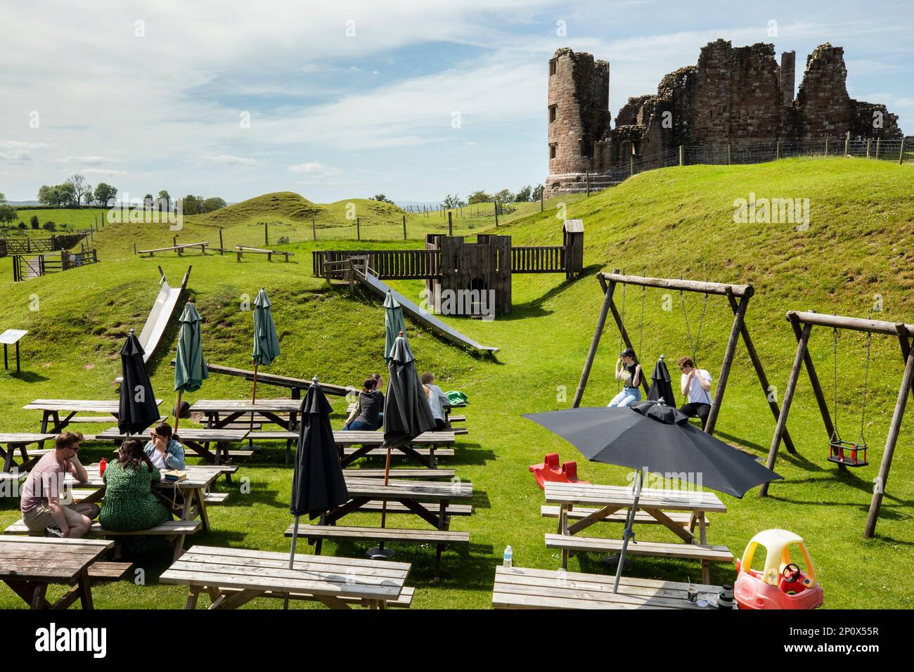 People sit an an outdoor cafe and playground in front of the 11th