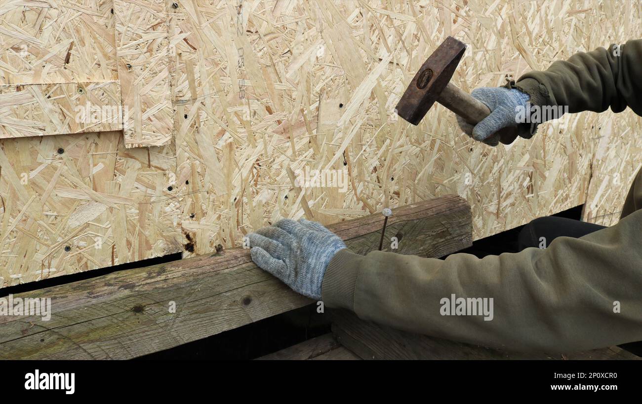 carpenter hitting a long nail with a hammer and hammering it into the