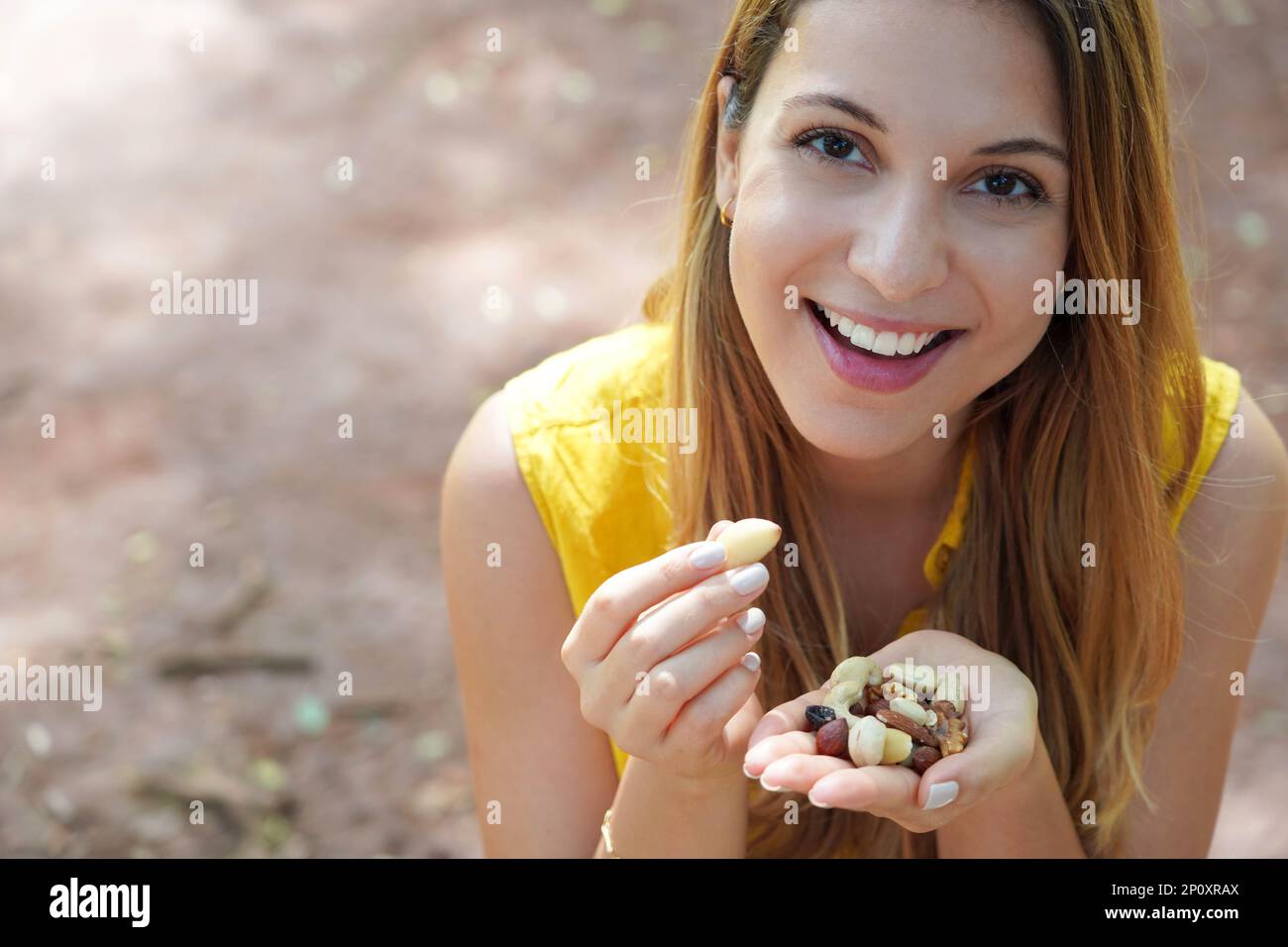 Healthy smiling girl eating a mix of nuts seed dried fruits looking at