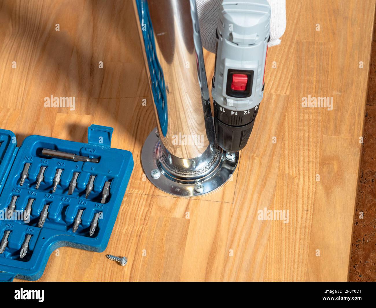 attaching table leg to wooden surface with screws and electric screwdriver Stock Photo