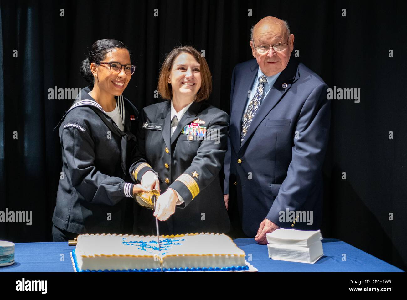 Rear Adm. Jennifer Couture, commander, Naval Service Training Command (NSTC), and Musician 3rd Class Sara Vega, and Ted Rock of the Lake County Navy League, cut the cake during the Lake County Navy League's Sailor of the Year (SOY) awards ceremony at the National Museum of the American Sailor in Great Lakes, Il. Jan. 25. More than 40,000 recruits train annually at the Navy's only boot camp. Stock Photo