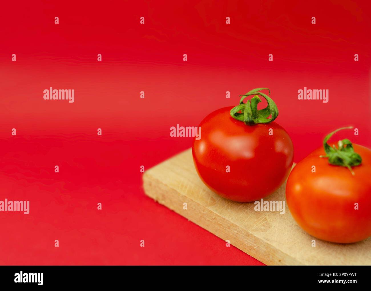 The two red tomatoes sit next to each other on a cutting board Stock ...