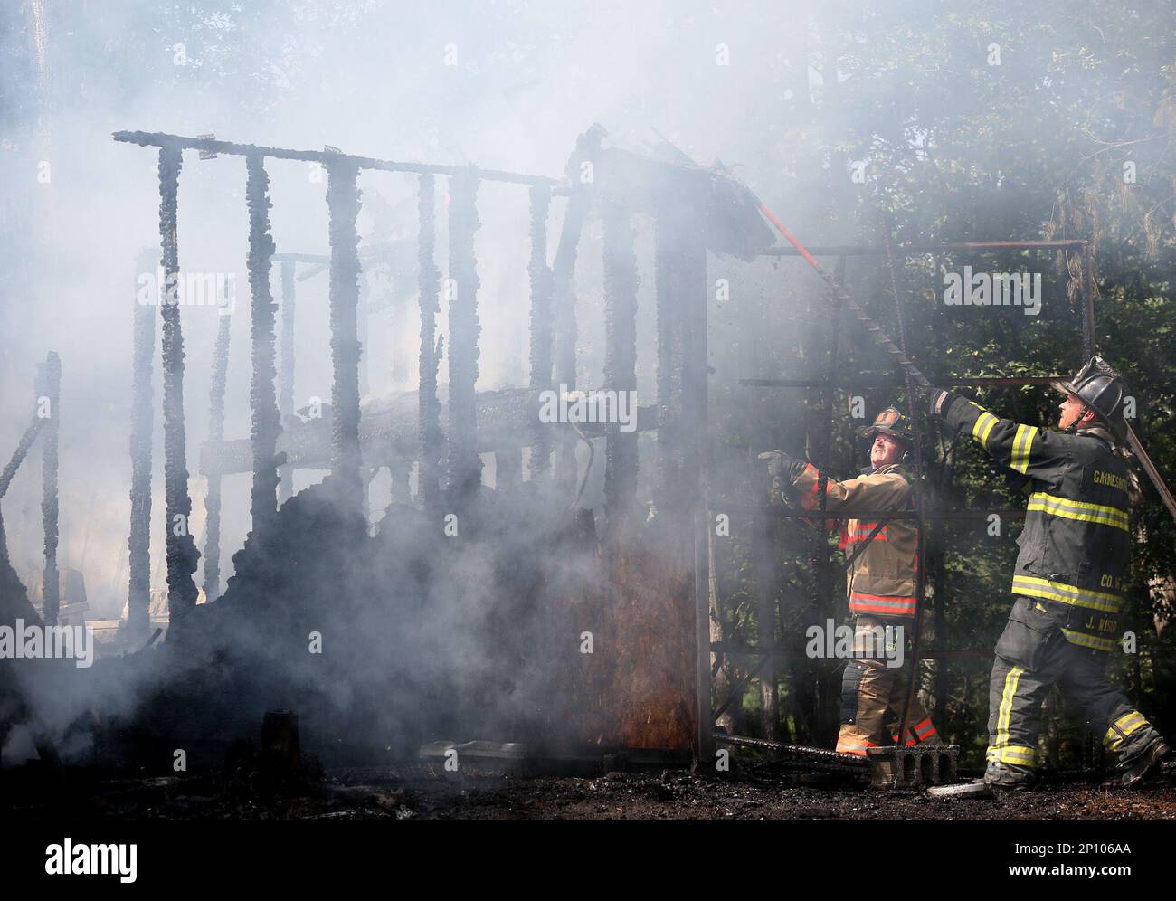 Firefighters Bobby Luttrell, left, and Jim Wisdo use pike poles to