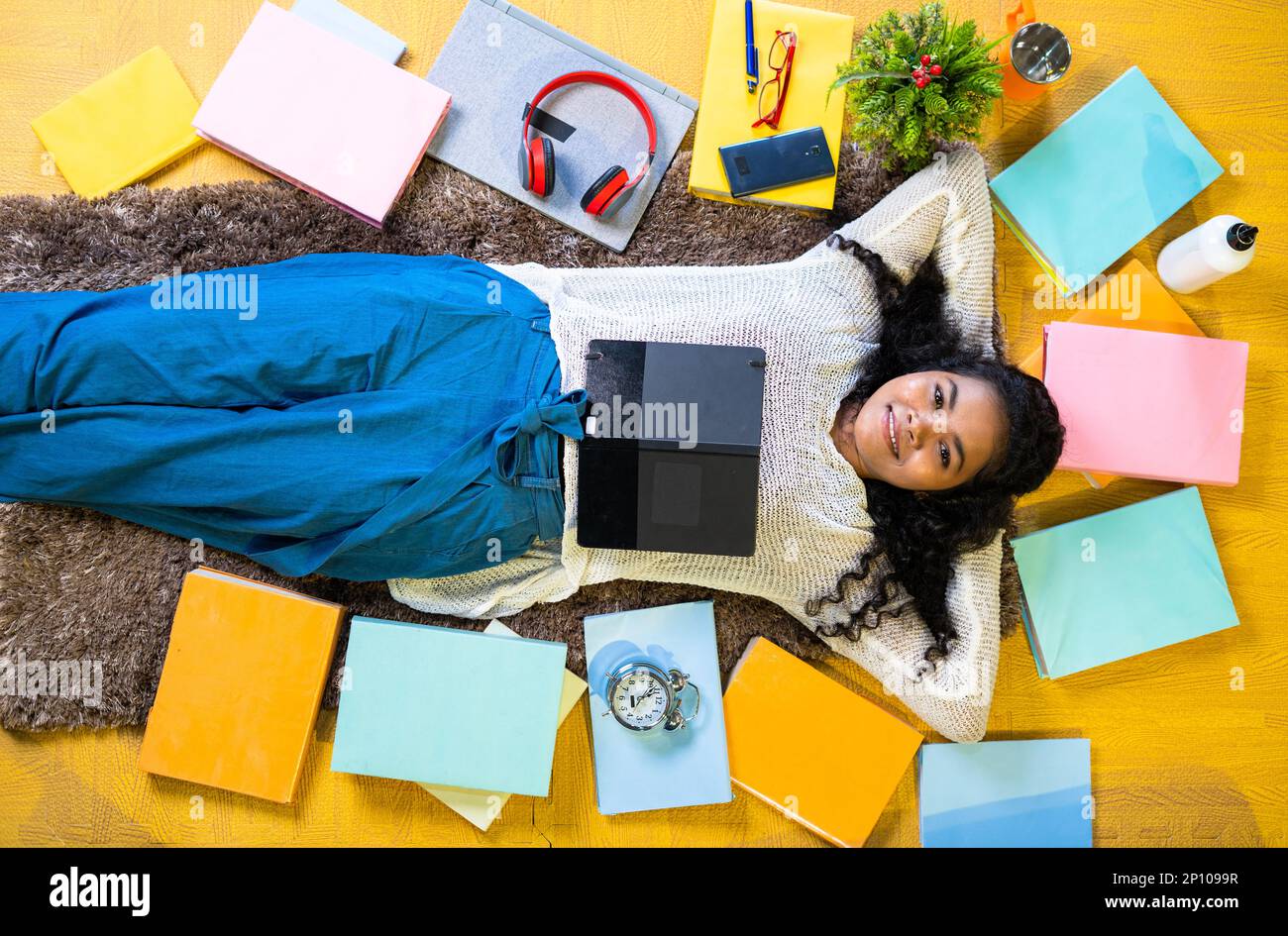 Top view flatlay shot girl sleeping with books around on floor by looking at camera while reading at home Stock Photo