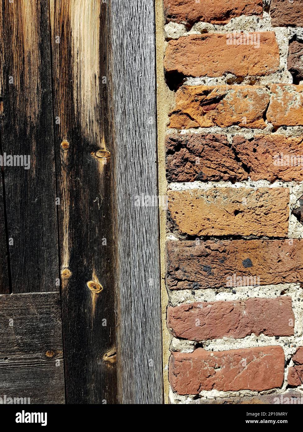 Detail from a traditional wooden door set into a red brick wall. Stock Photo