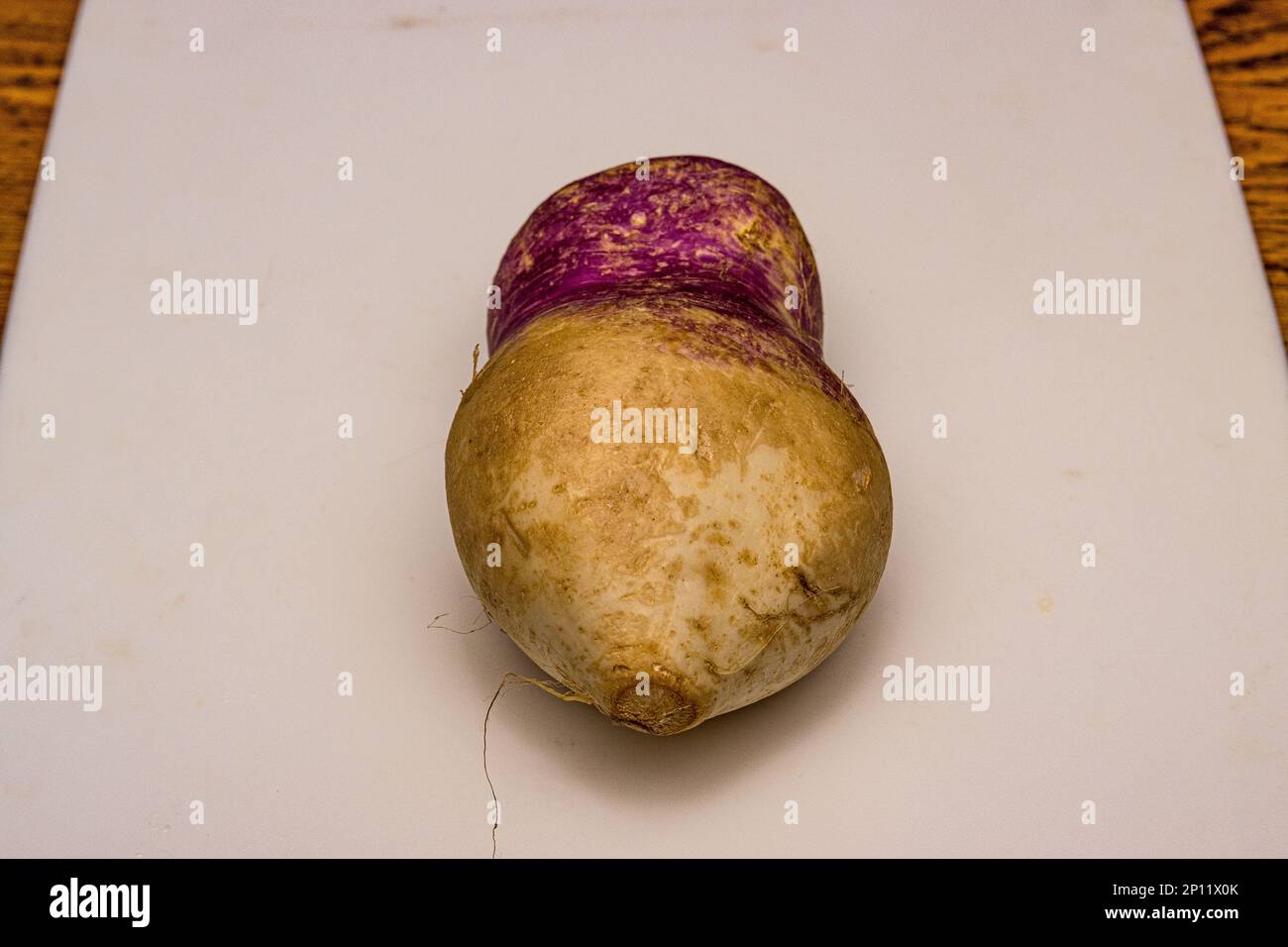 A common turnip with an odd shape on a kitchen cutting board Stock Photo