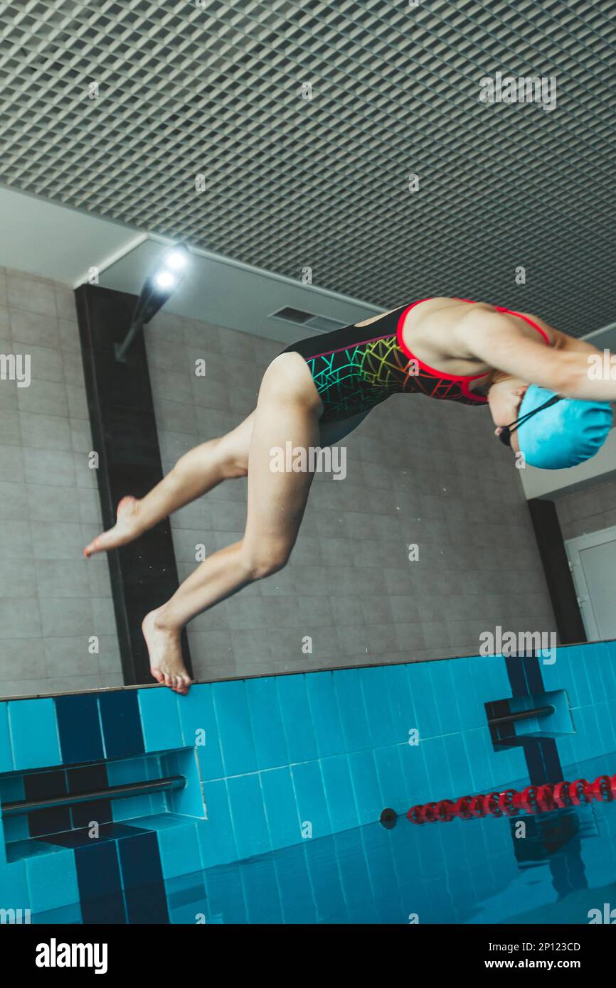The girl is engaged in synchronized swimming in the pool. Pool jump trick. The swimmer jumps