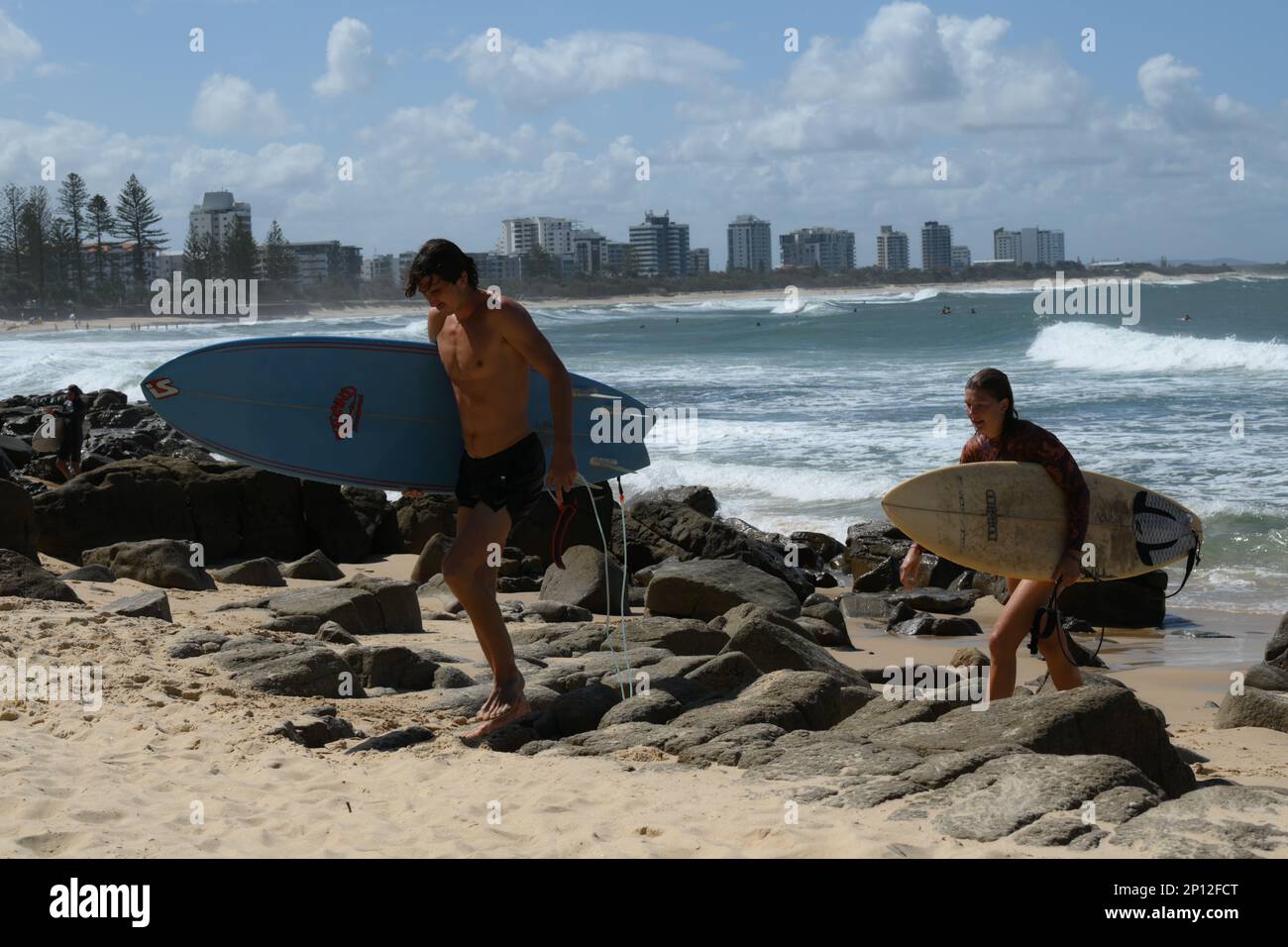 Alexander point, 2 surfers leave the surf, Maroochydore high rises in background. Stock Photo