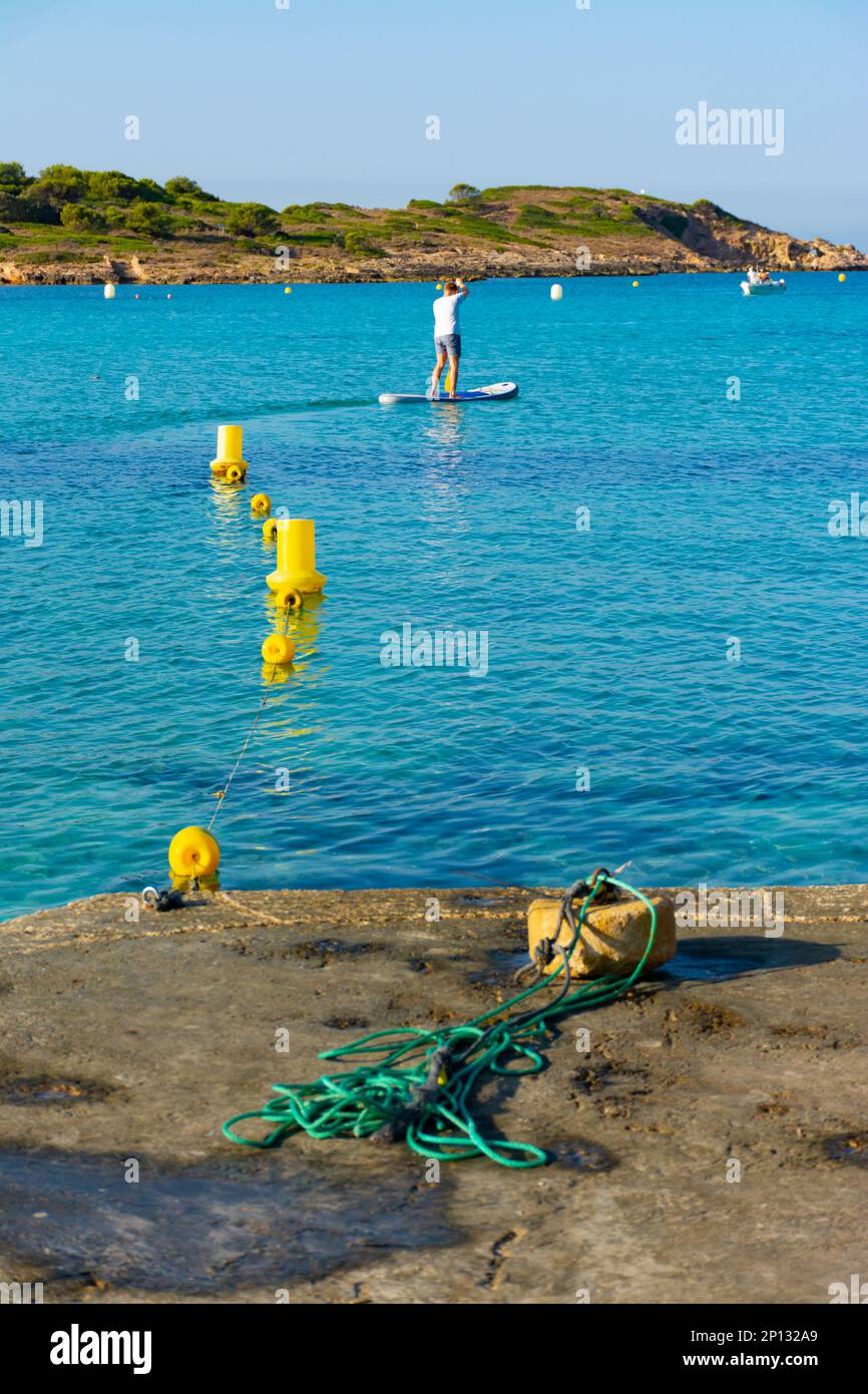 Ses Illetes, Majorca, Balearic Islands, Spain. July 20th, 2022 - Buoys and mooring stone in Cala Xinxell, with the tower of the island of Sa Torre. Ma Stock Photo