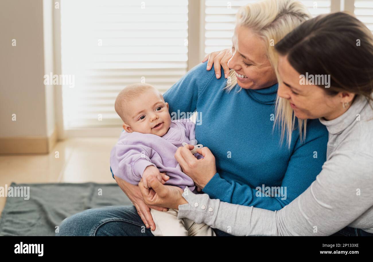 Happy lesbian couple having tender moments with their small baby at home - LGBT Family concept Stock Photo