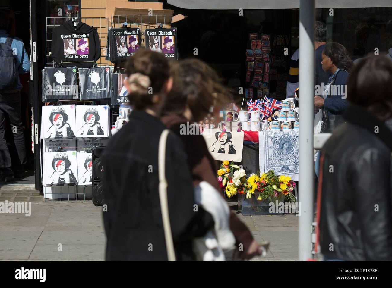 Images of the late Queen Elizabeth II are seen as people queue and wait ...