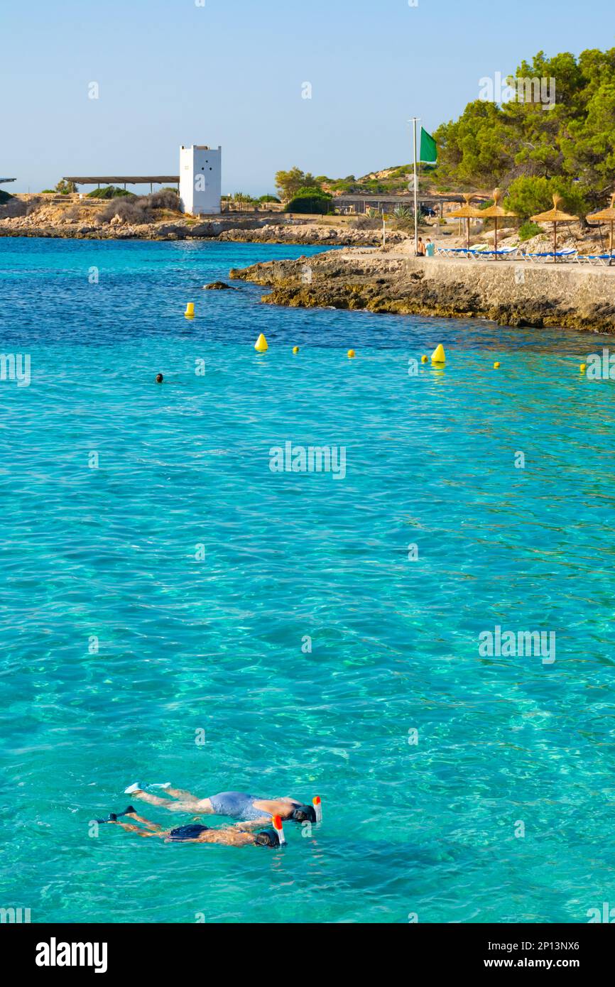 Cala Comtesa cove, Ses Illetes, Majorca, Balearic Islands, Spain. July 20th, 2022 - People snorkeling in the cove, next to the rocky coast with umbrel Stock Photo
