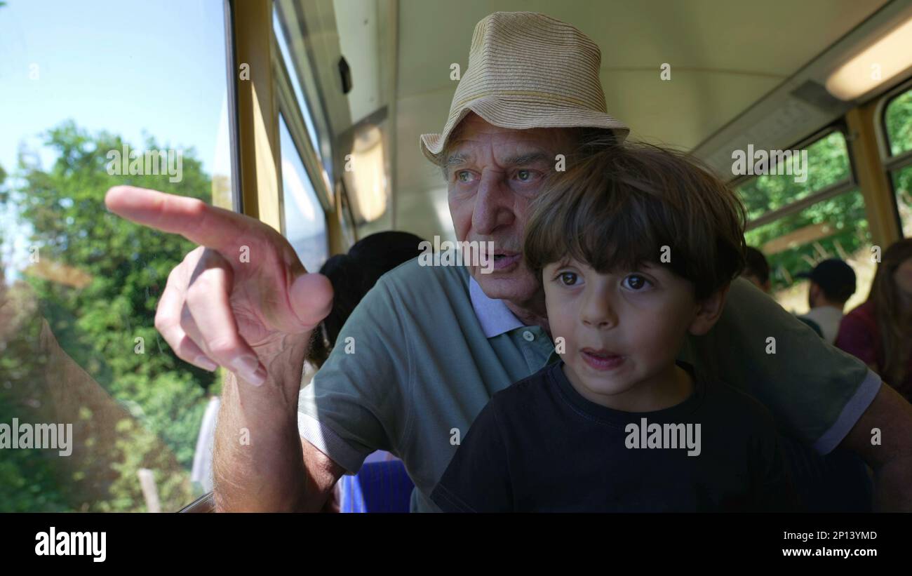 Happy grandfather traveling by train with grandchild together. Senior ...