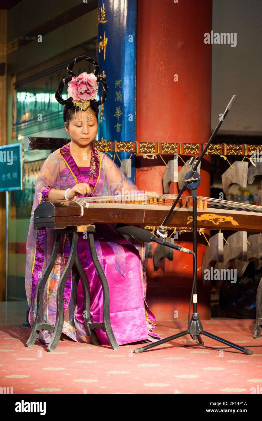 Female musician on a traditional string instrument, perhaps the guzheng