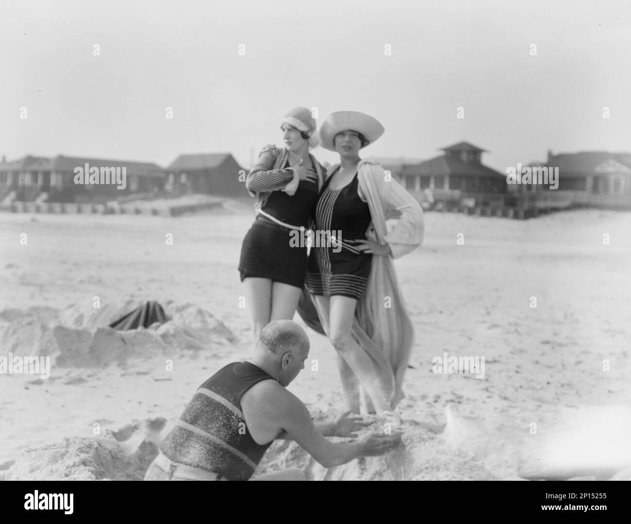 Unidentified man building sand castle and two women, Long Beach, New York, between 1911 and 1942. Stock Photo