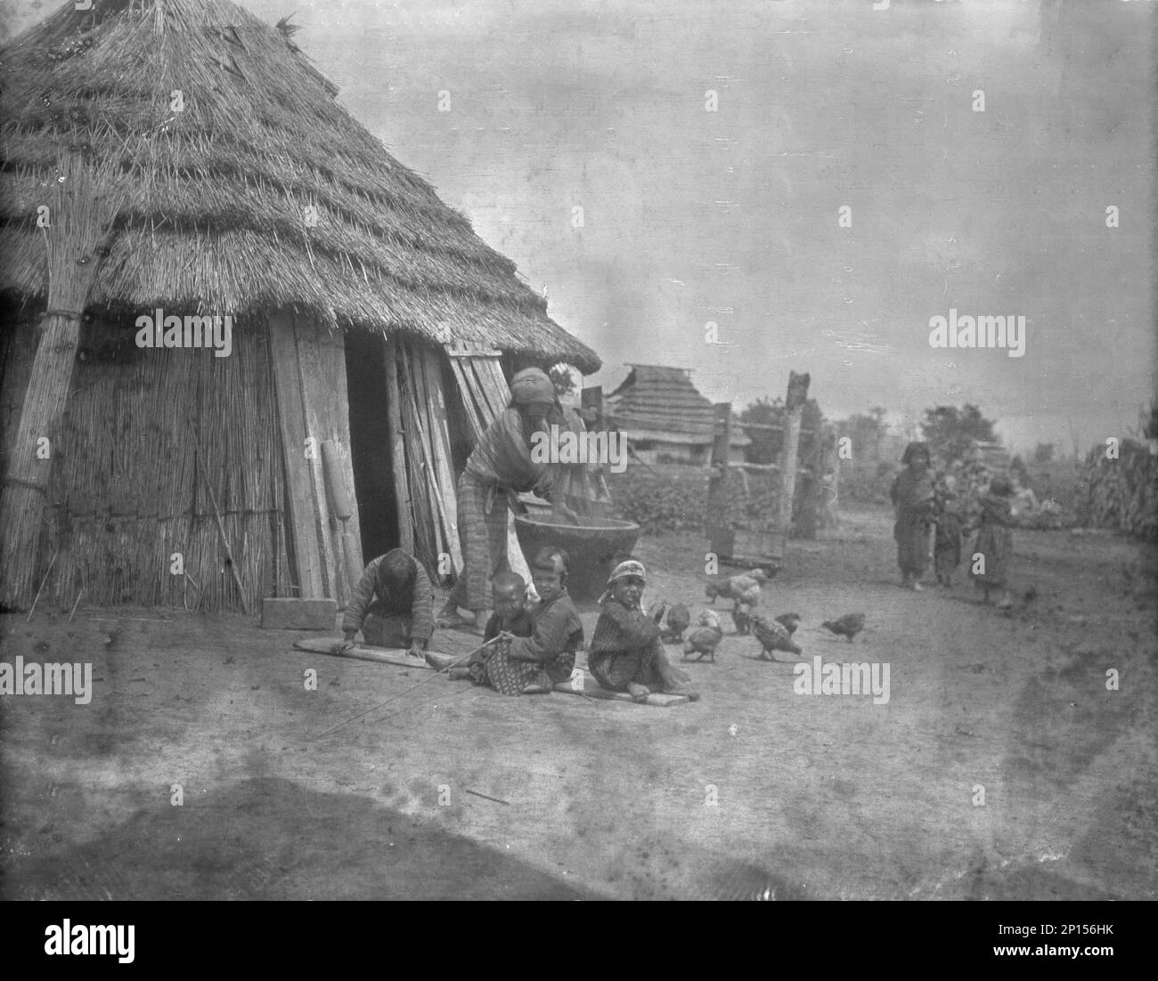 Ainu women and children outside a hut, 1908. Stock Photo