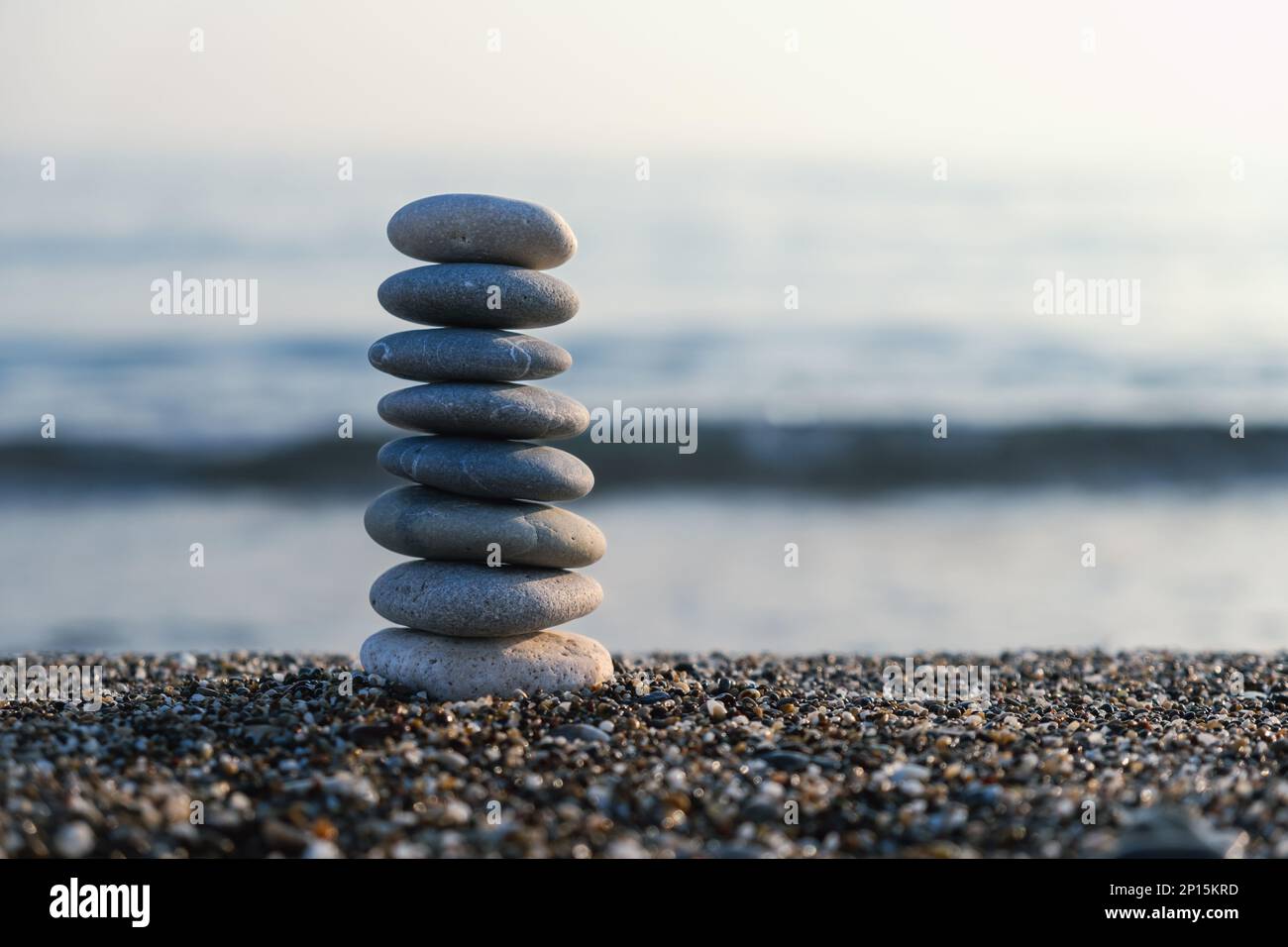 Balanced pebble pyramid at the beach. Selective focus Abstract bokeh with Sea on the background. Zen stones on the beach, meditation, spa, harmony. Stock Photo
