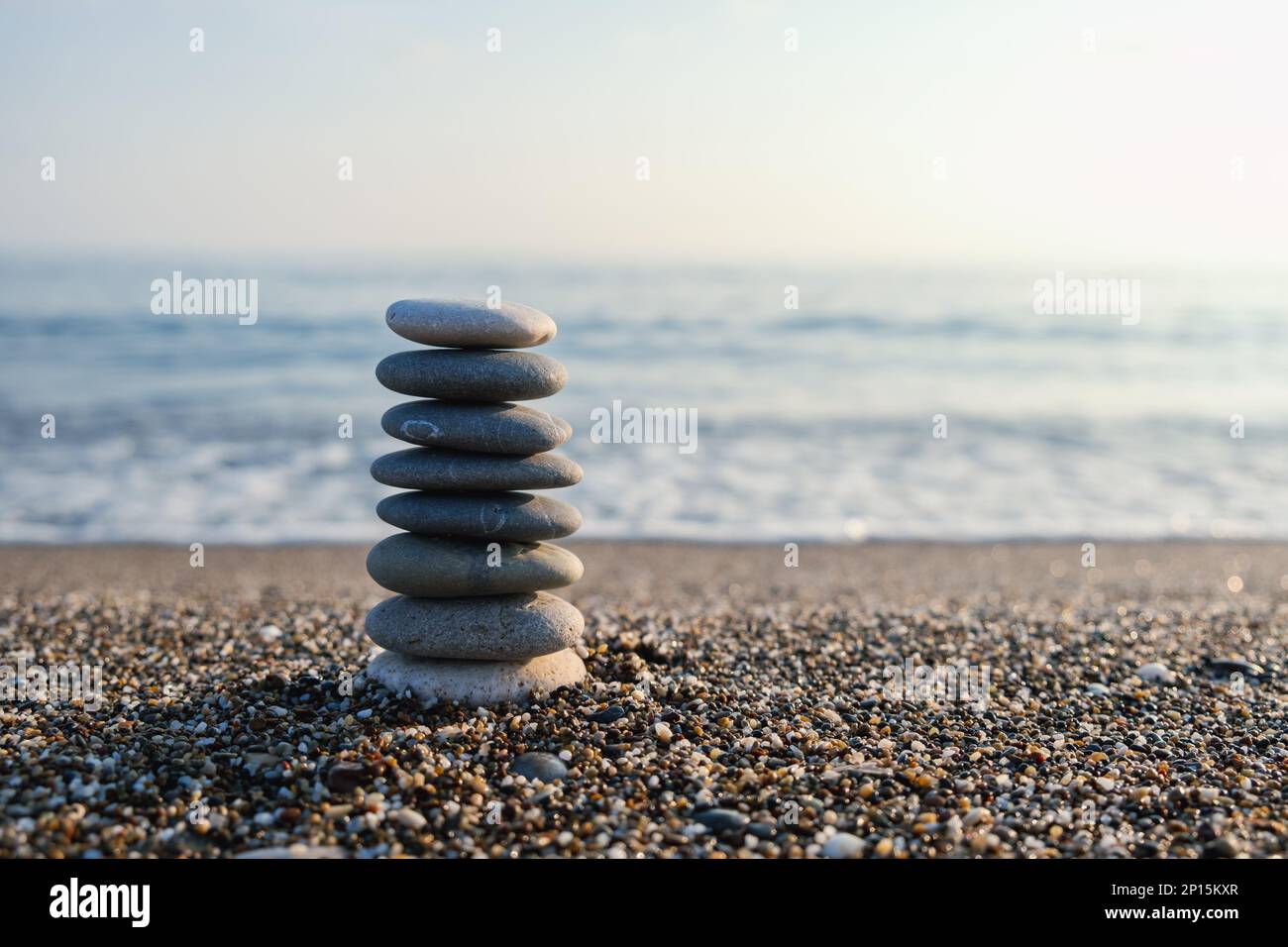Balanced pebble pyramid at the beach. Selective focus Abstract bokeh with Sea on the background. Zen stones on the beach, meditation, spa, harmony. Stock Photo