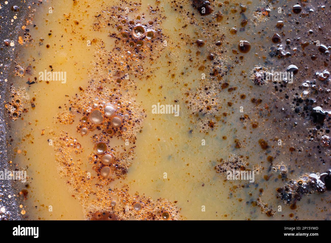 Burned oily leftover grease fat in a pan macro shot air bubbles top