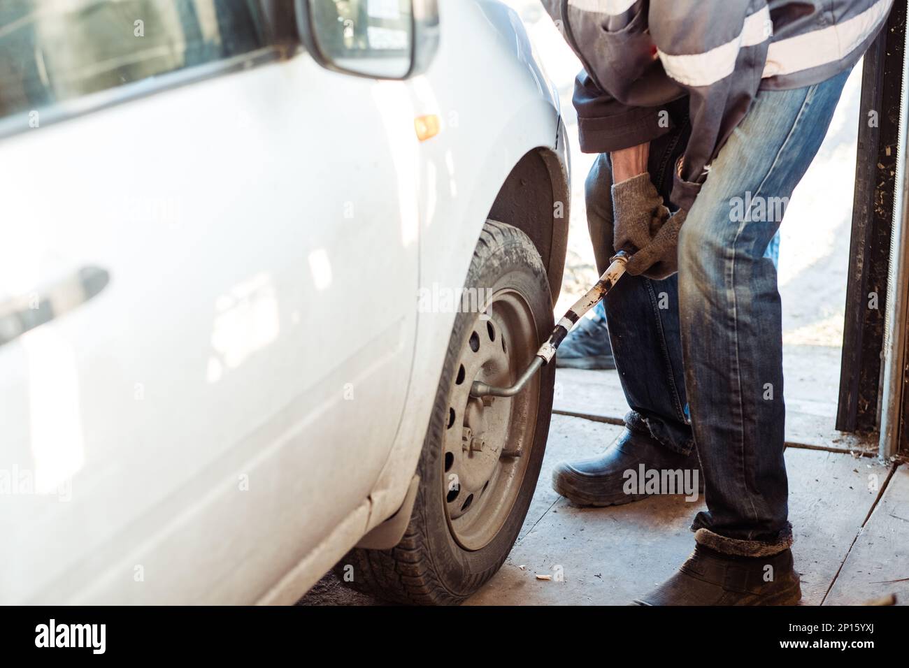Mechanic changing a car tire in a on a car using an electric
