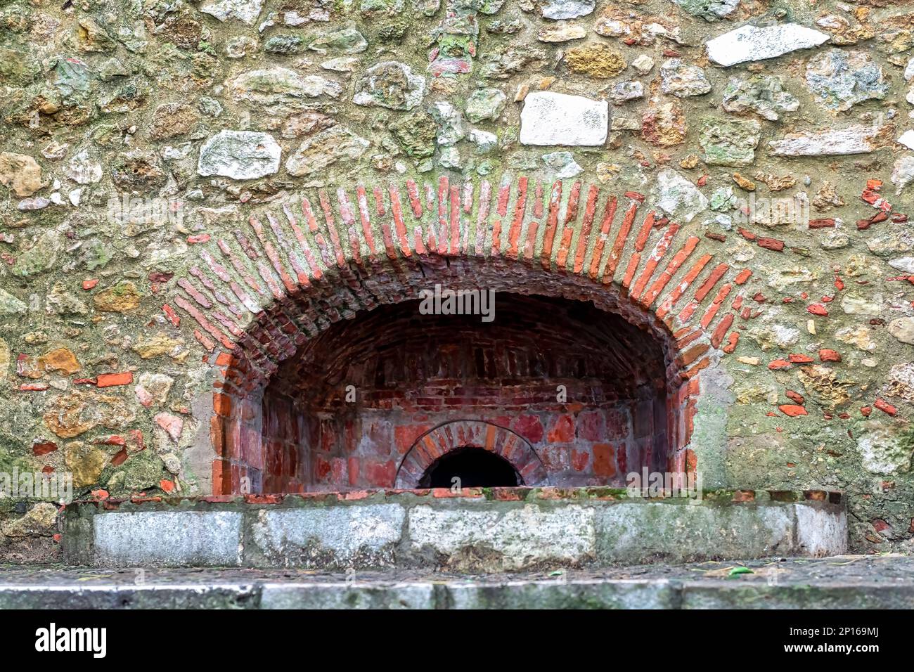 A brick arched structure in the stone wall of the old fortress. Stock Photo