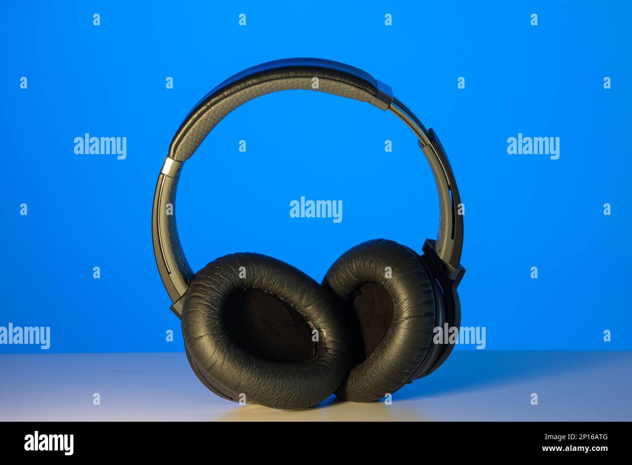 Generic black Bluetooth wireless headphone isolated on blue background. Stock Photo