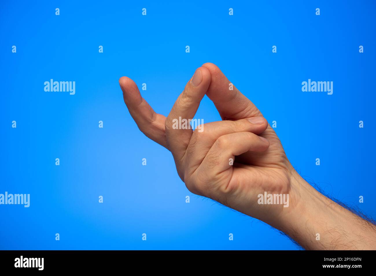 Caucasian male hand making a finger snap gesture studio shot isolated on blue background. Stock Photo