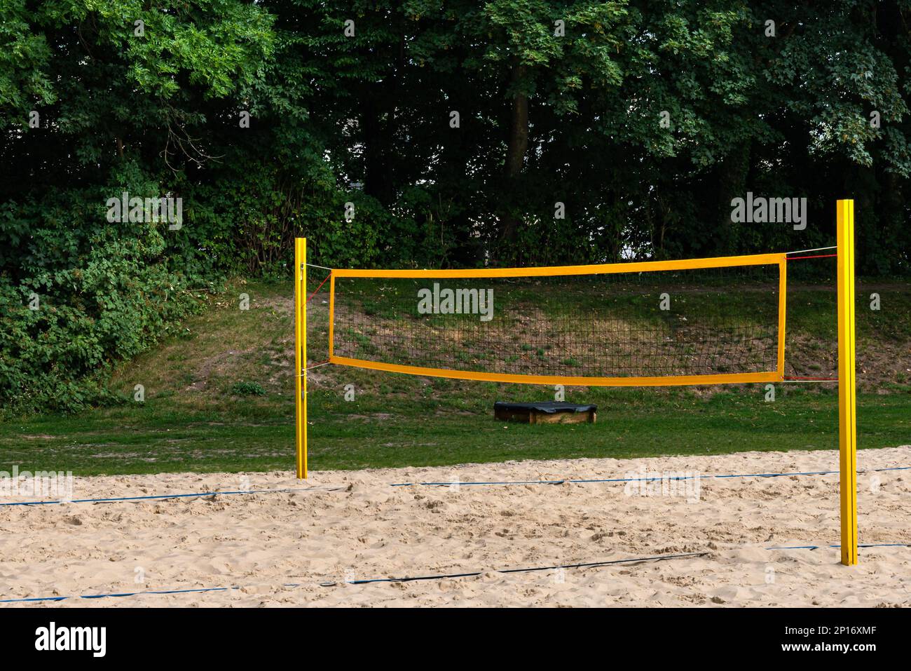 Playground for playing beach volleyball with a bright yellow net. green trees in the background