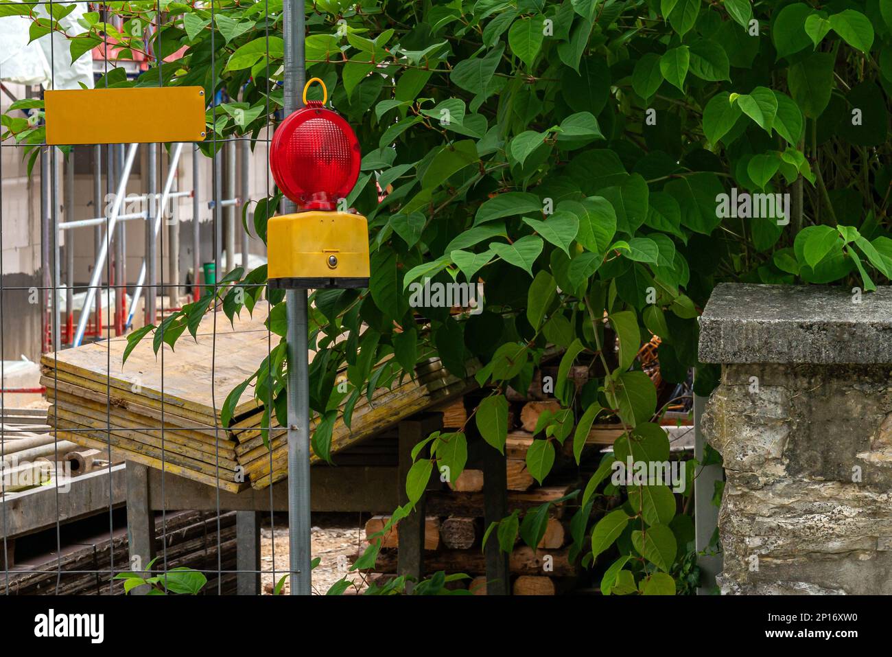 Street barricade with warning signal lamp on a fence. Construction safety. Stock Photo