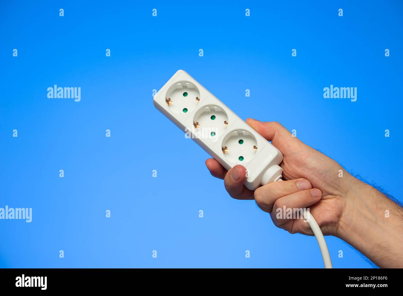 Electrical extension cord with multiple plug sockets held in hand by