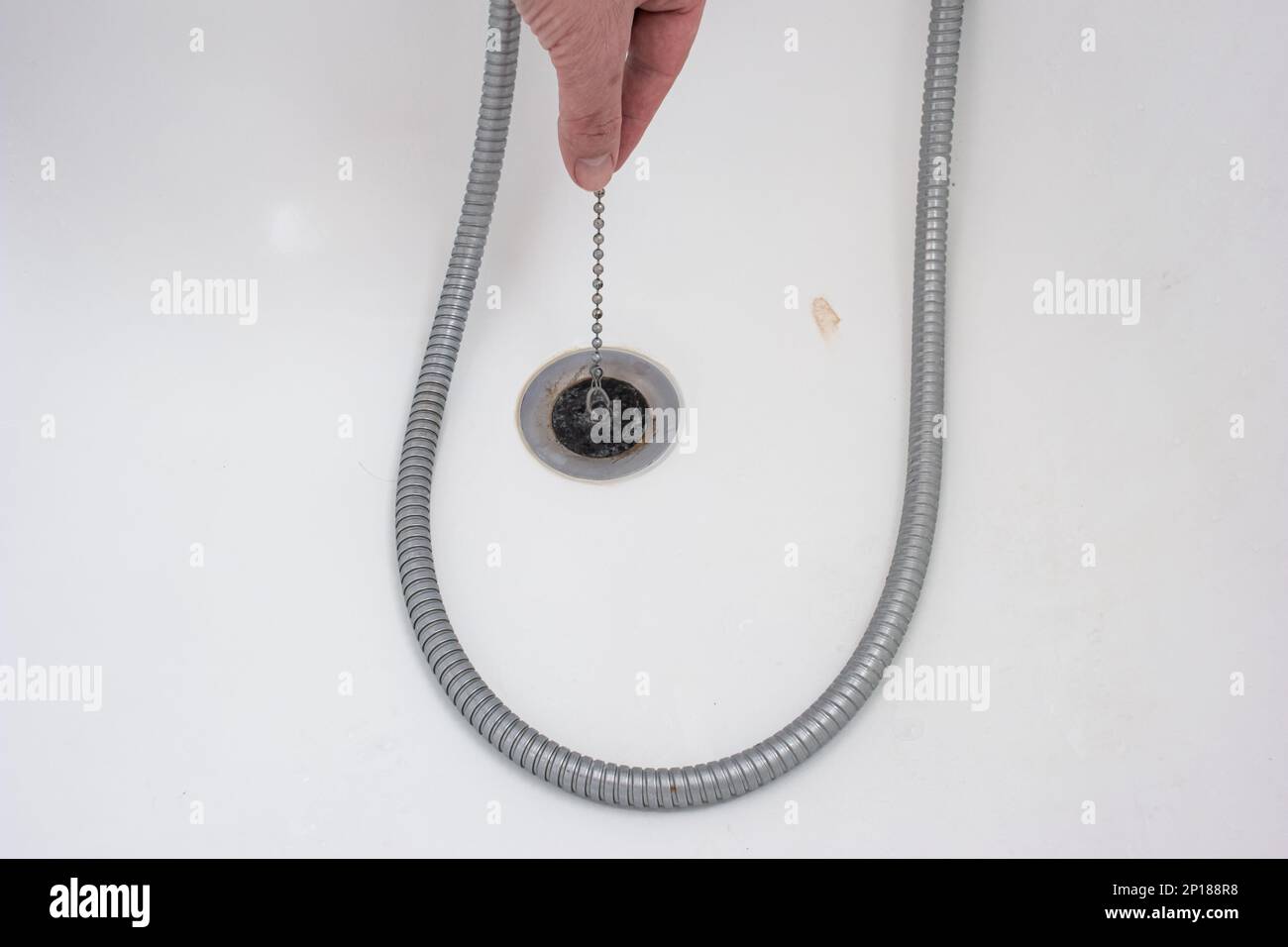 Caucasian male hand holding a bathtub rubber plug on a chain next to