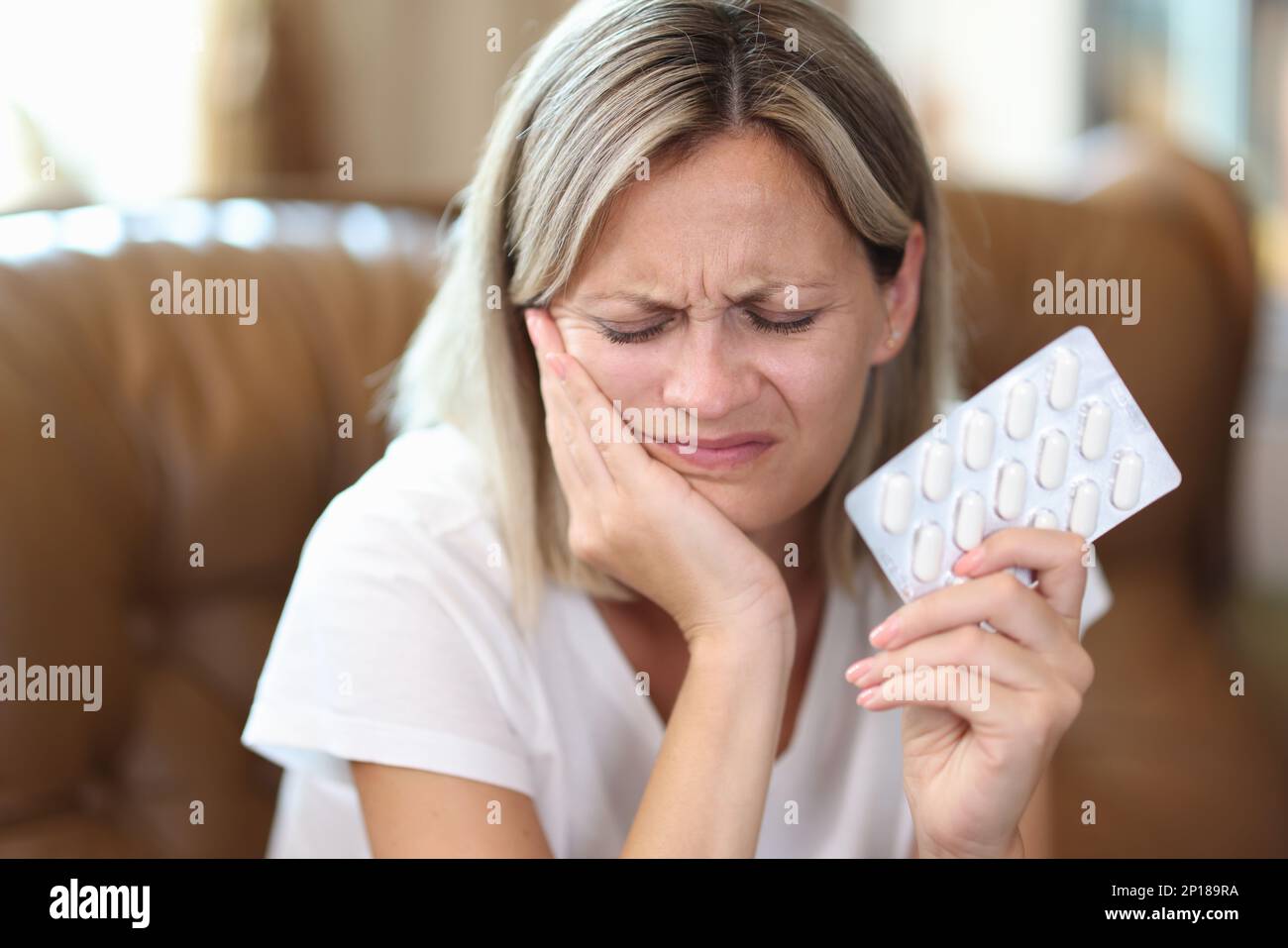 Woman suffering from toothache holding painkillers in hand Stock Photo