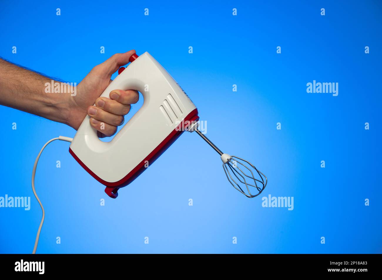 Electric food mixer held in hand by Caucasian male hand studio shot