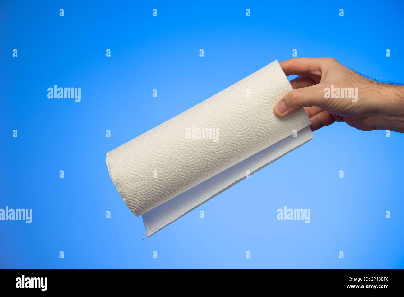 Kitchen paper roll wipes held in hand by Caucasian male hand studio